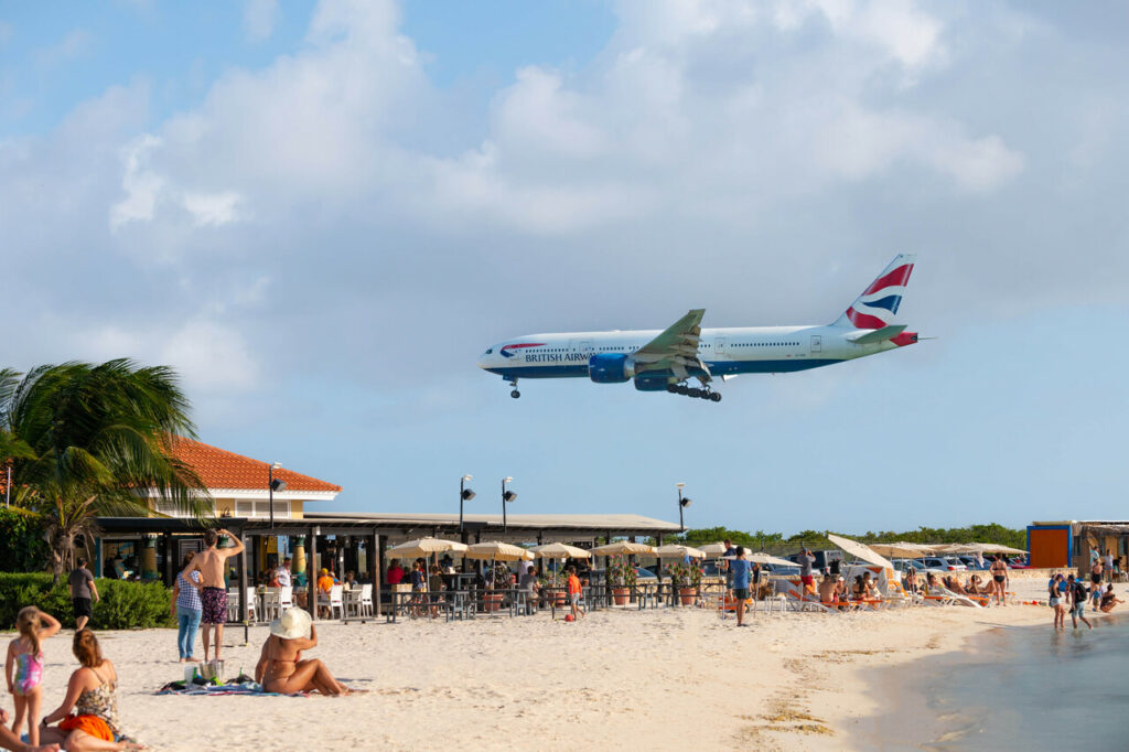A British Airways flight passes over a Caribbean beach.