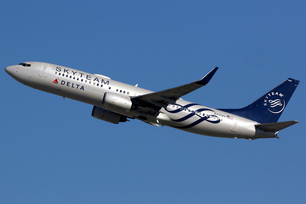 A Delta aircraft in SkyTeam livery climbs out.