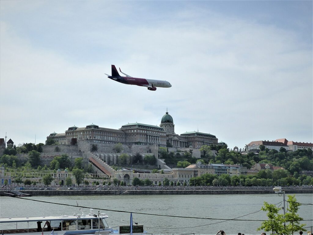 A Wizz Air aircraft banks low over the city.