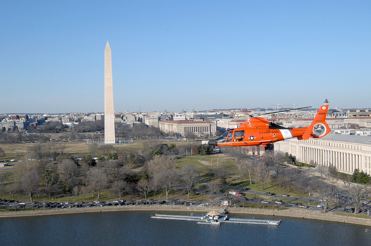 A Coast Guard helicopter flies past Washington Memorial in Washington DC.