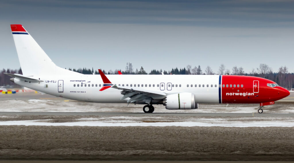 A Norwegian Boeing 737 lined up on the runway.
