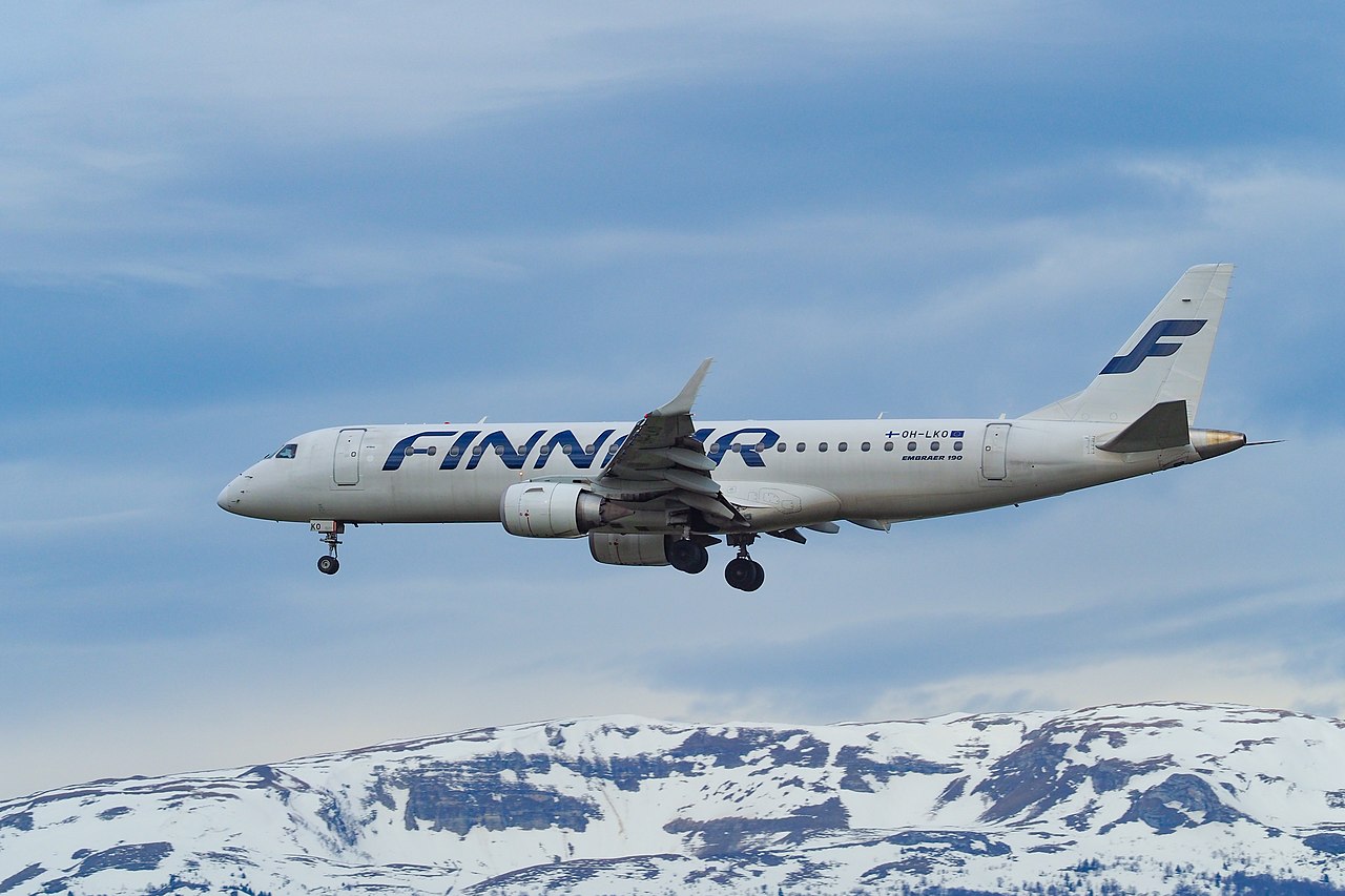 A Finnair Embraer flying over mountains.
