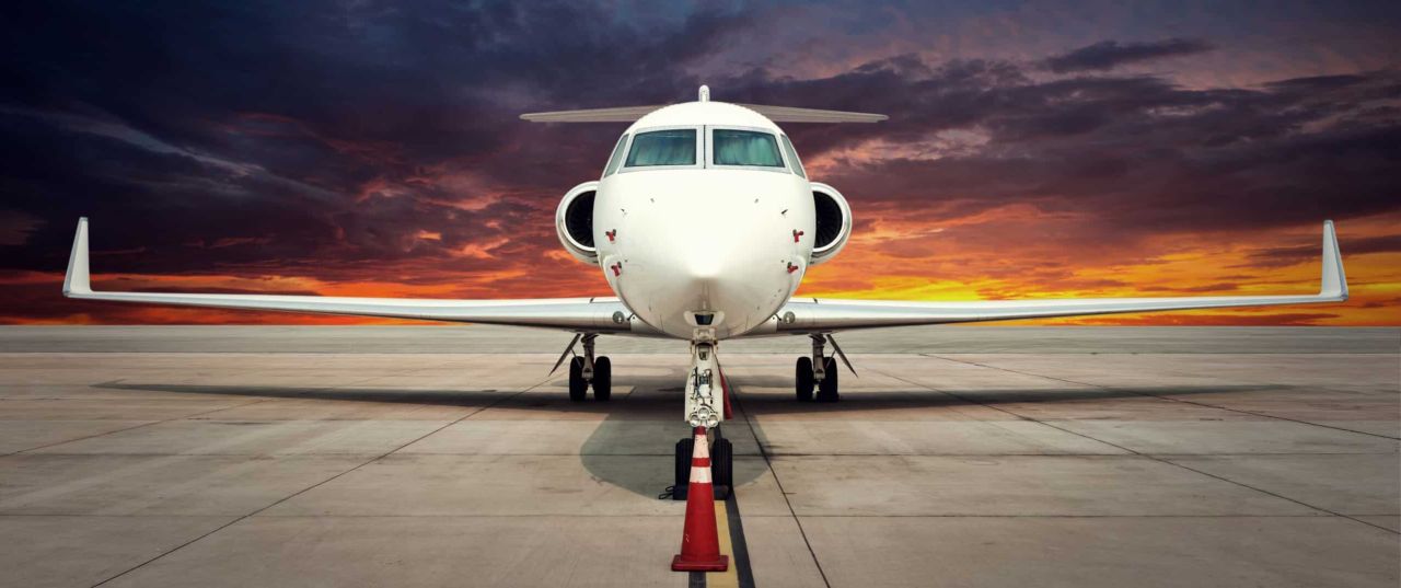 An Exquisite Air Charter business aviation jet parked on the tarmac at dusk.