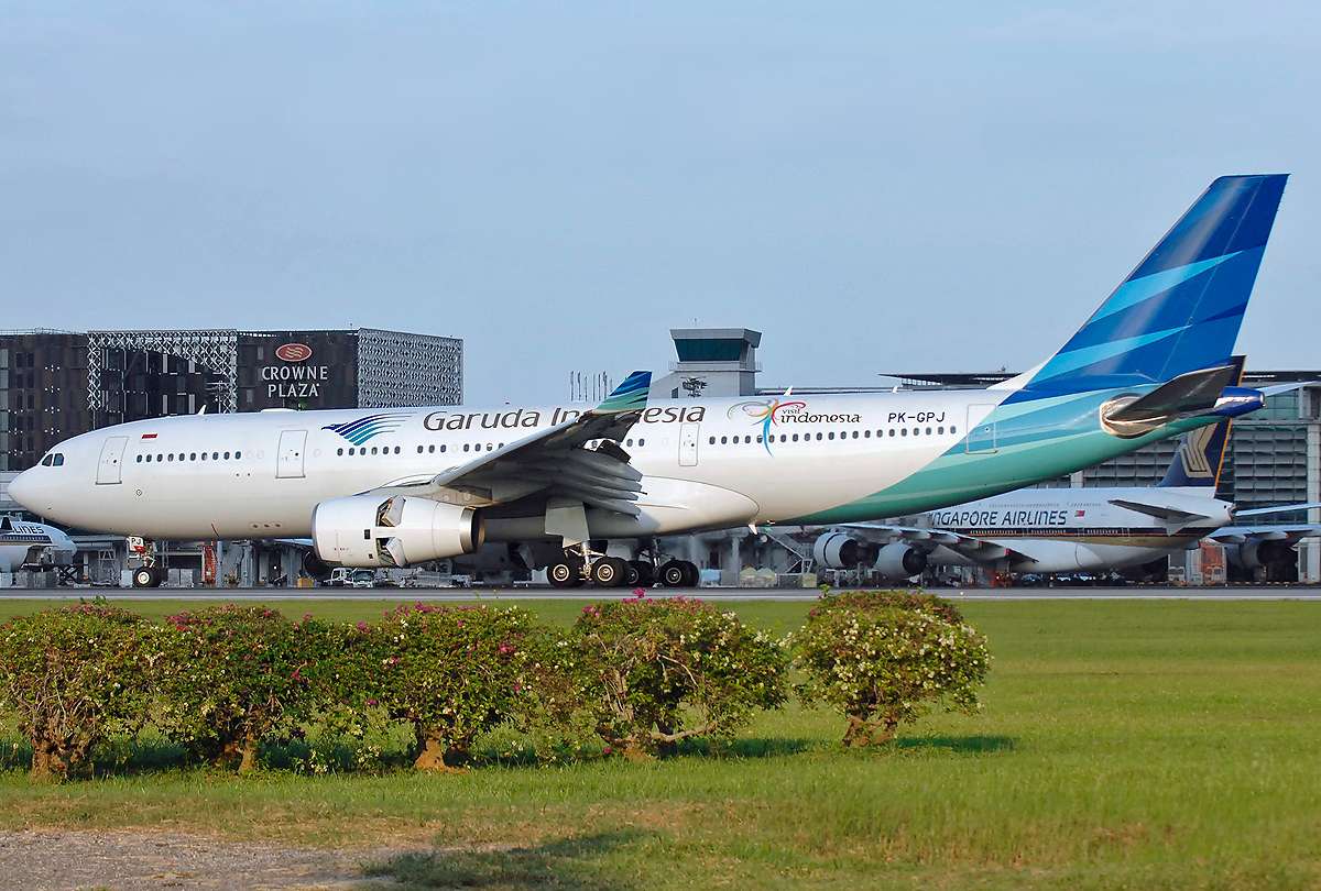A Garuda Airbus passes a parked Singapore Airlines aircraft.
