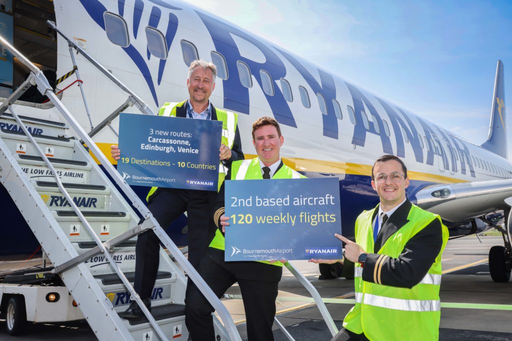 Staff hold up travel signs in front of an aircraft at Bournemouth Airport.