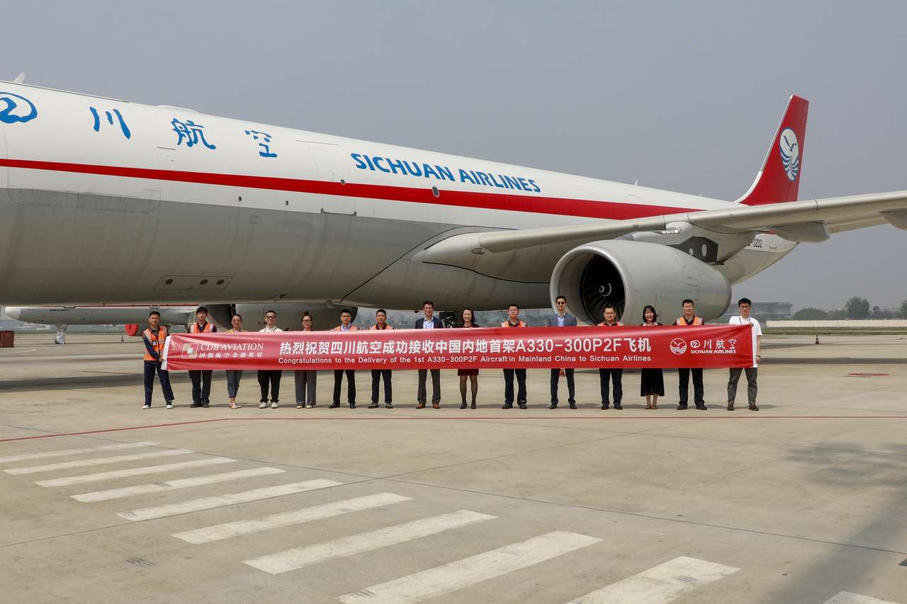 Staff hold a banner in front of new Sichuan Airlines A330 freighter aircraft.