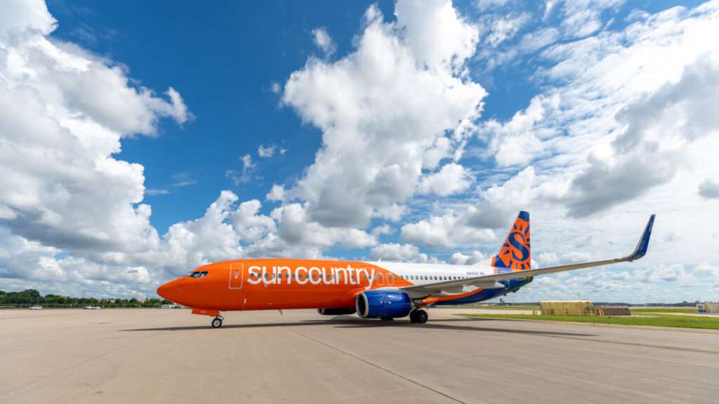 A Sun Country Airlines Boeing parked under a blue sky.