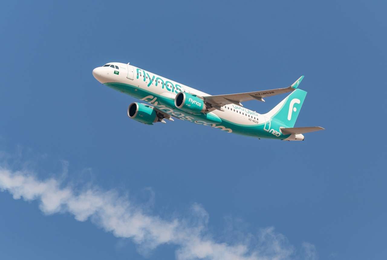 A flynas aircraft passes overhead.