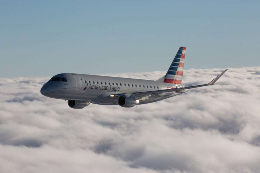 An American Eagle Embraer E175 in flight above cloud.