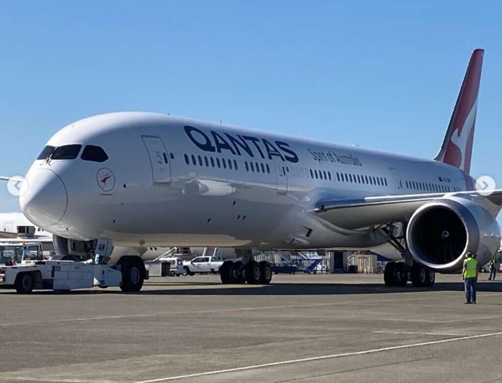 A Qantas Boeing 787 is marshalled to the parking area.