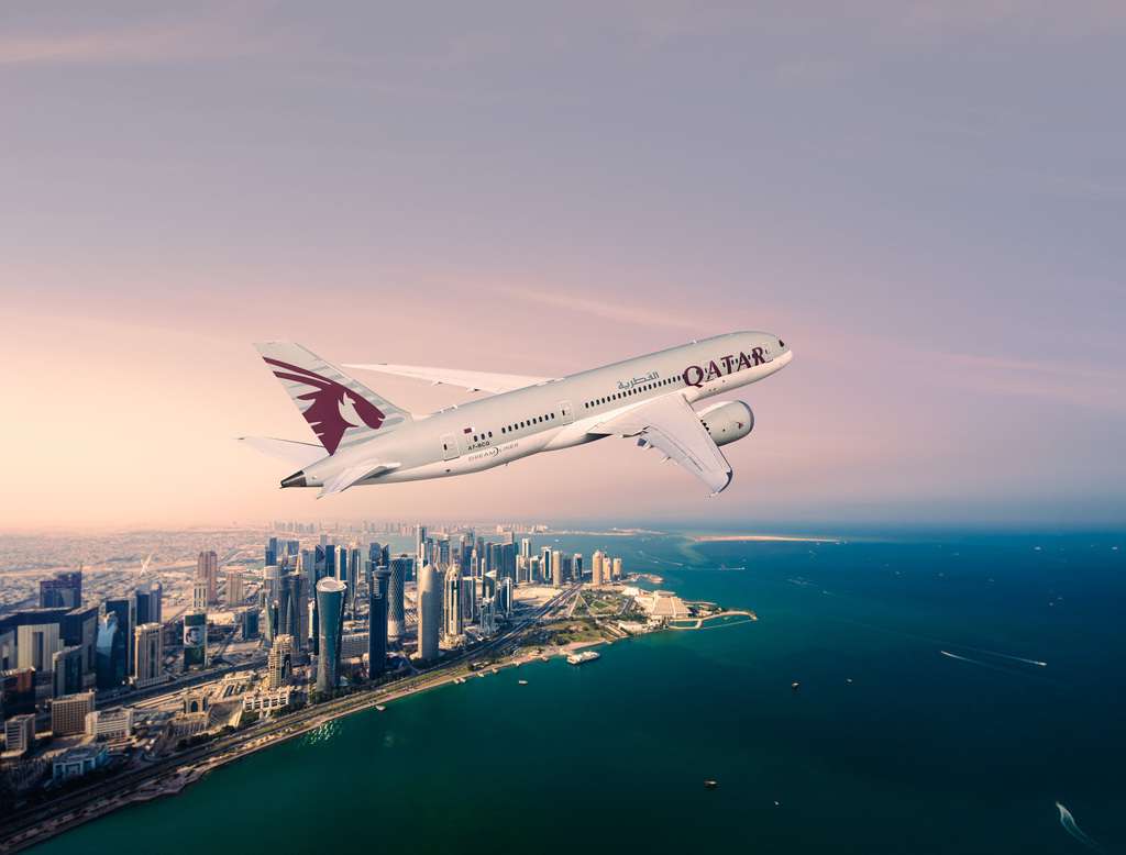 A Qatar Airways aircraft passes over the city.