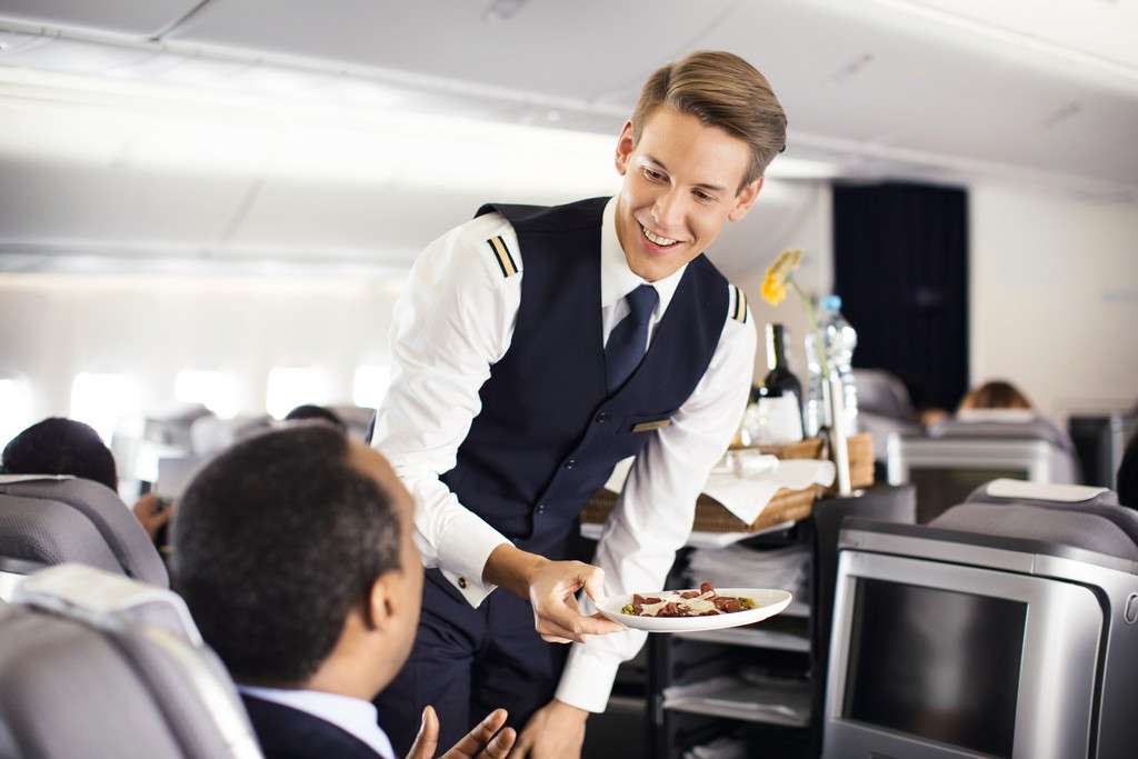 A Lufthansa flight attendant offers food to a passenger.