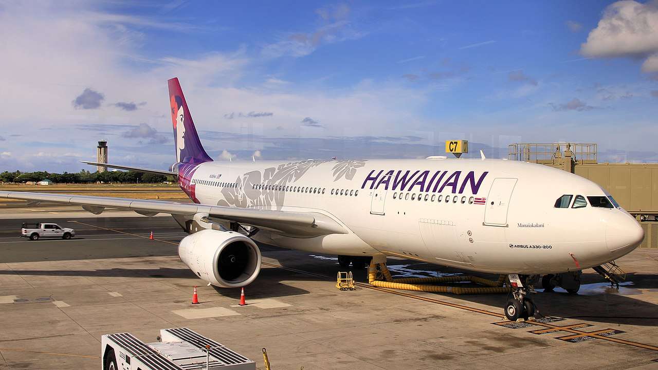 A Hawaiian Airlines Airbus A330 parked at the terminal gate.