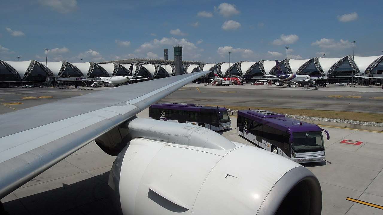 Buses parked with Thai Airways aircraft on tarmac in Bangkok.