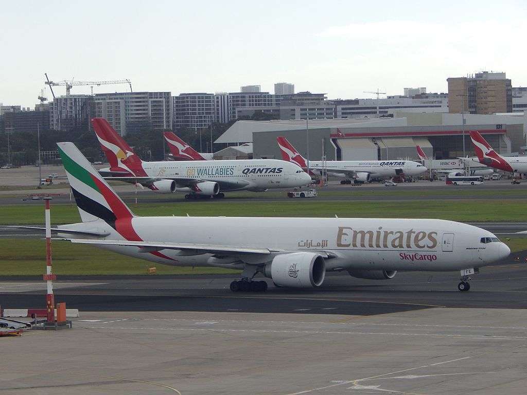 An Emirates cargo aircraft passes a line of parked Qantas aircraft in Sydney.
