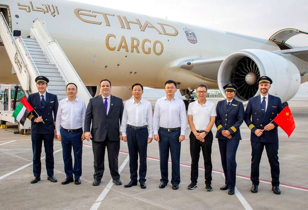 Members of Ezhou Airport and Etihad Cargo stand in front of an air cargo freighter.
