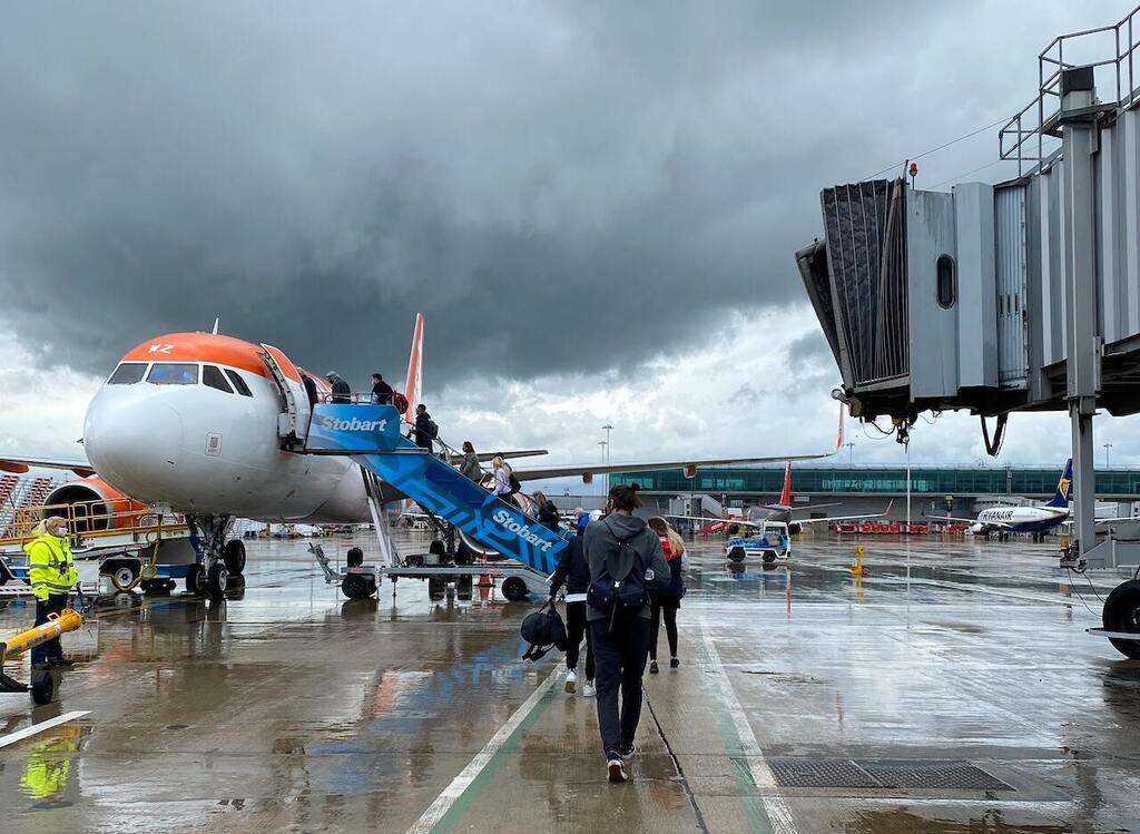 Passengers board a jet in stormy weather.