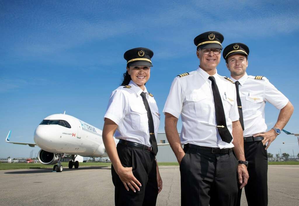 Air Transat pilots stand in front of an Airbus aircraft.
