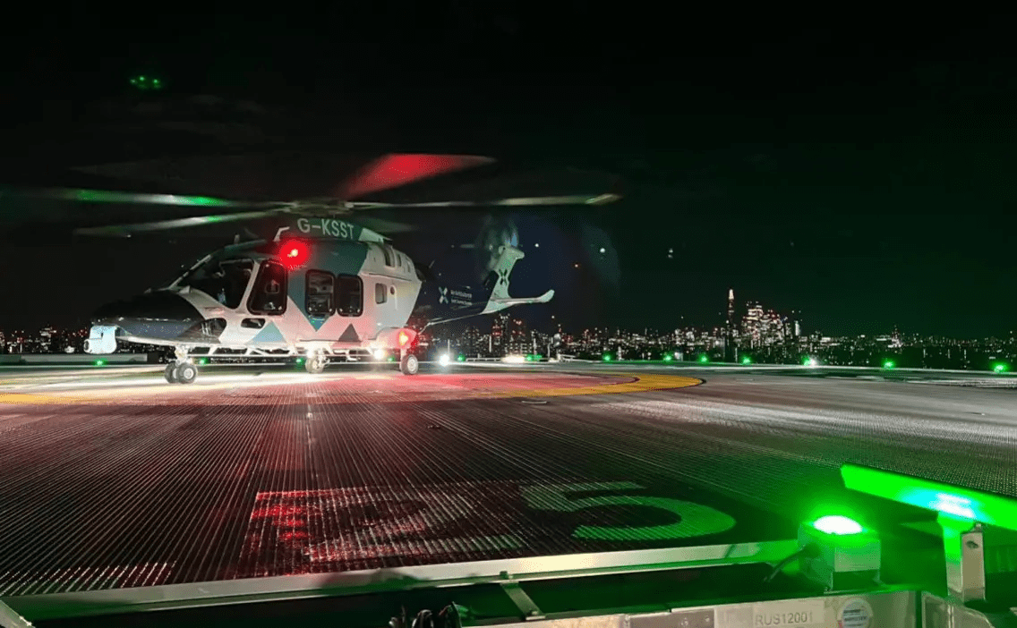 A Kent Surrey Sussex Air Ambulance helicopter on the helipad at night.