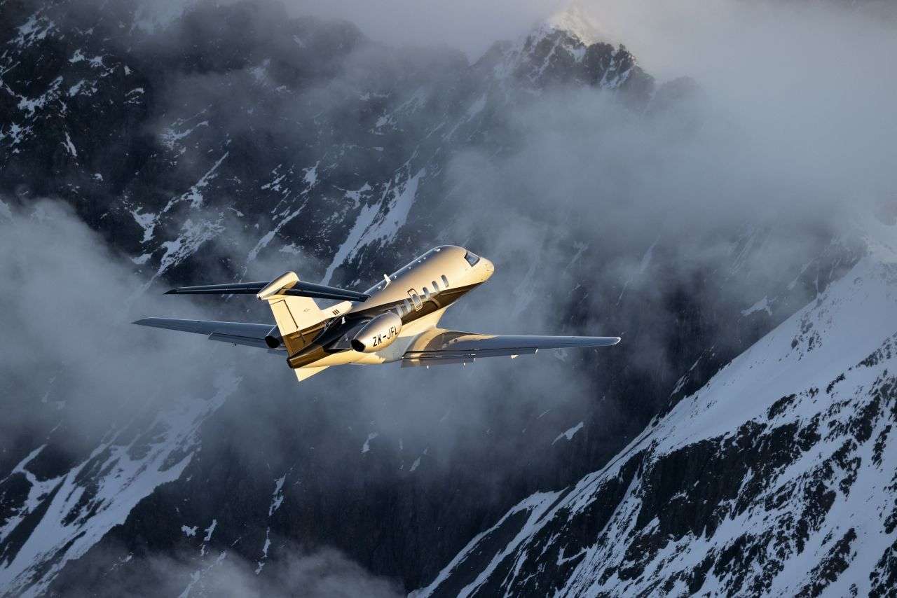 A Pilatus PC-24 in flight over mountains.