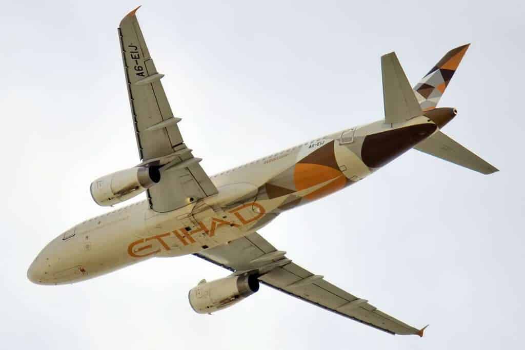 An Etihad Airways A320-232 passes overhead.
