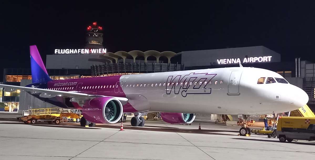 A Wizz Air flight parked at Vienna Airport at night.