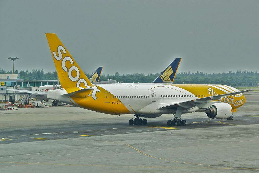 A Scoot Boeing 777 taxis past a Singapore Airlines aircraft.