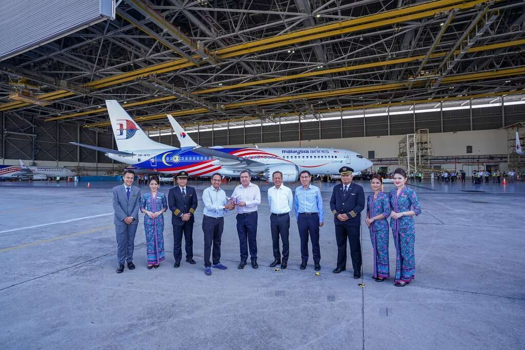 Malaysia Airlines staff with Boeing 737-8 aircraft in hangar.