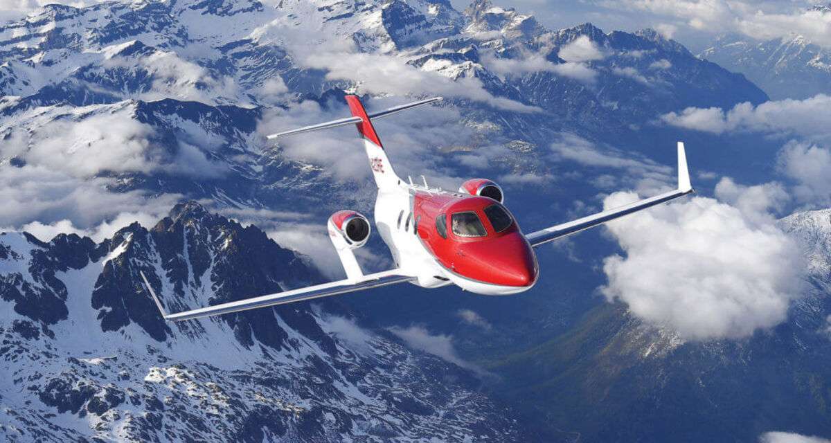 A Honda Jet in flight above mountains.