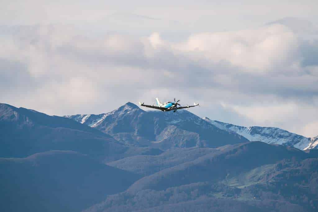 An Airbus EcoPulse aircraft in flight over mountains.