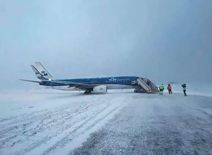 A KLM Boeing 737 parked off the taxiway at Gothenburg Airport in snow.