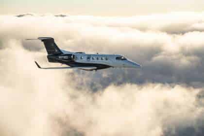 An Embraer Phenom 300 light jet in flight above cloud.