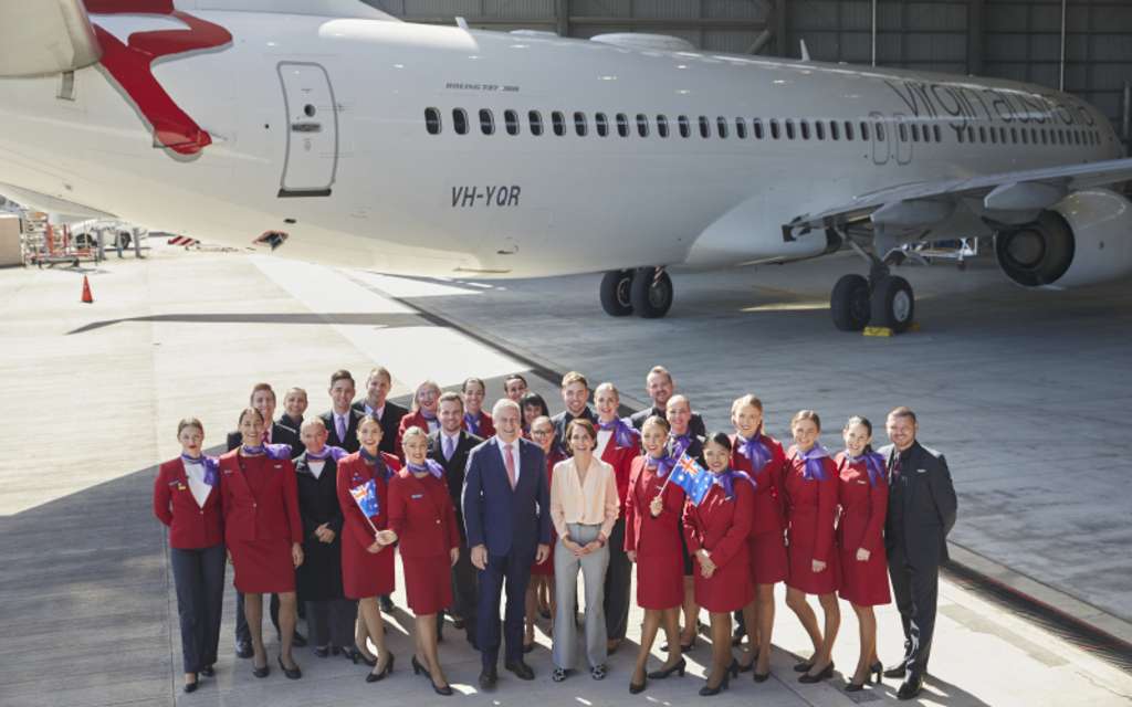 Virgin Australia CEO Jayne Hrdlicka and staff stand with a Virgin aircraft at the hangar.
