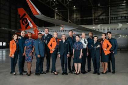 Jetstar staff in new uniforms with aircraft in hangar.
