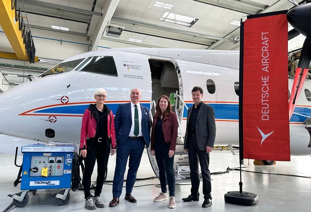 Coordinator for Aerospace Policy with Deutsche Aircraft staff in hangar with D328 test aircraft.