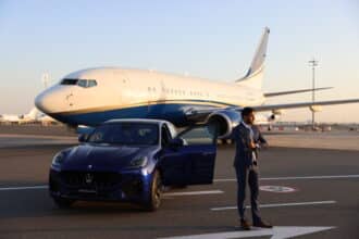 A Maserati parked in front of a RoyalJet Boeing aircraft.