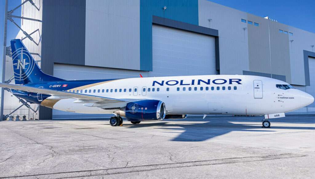 A Nolinor Boeing 737-400 parked in front of the hangar.