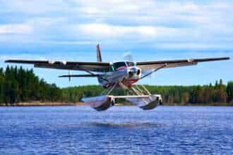 A Northway Aviation Cessna floatplane lands on a lake.