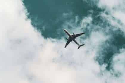 An airliner passes overhead in a cloudy sky.