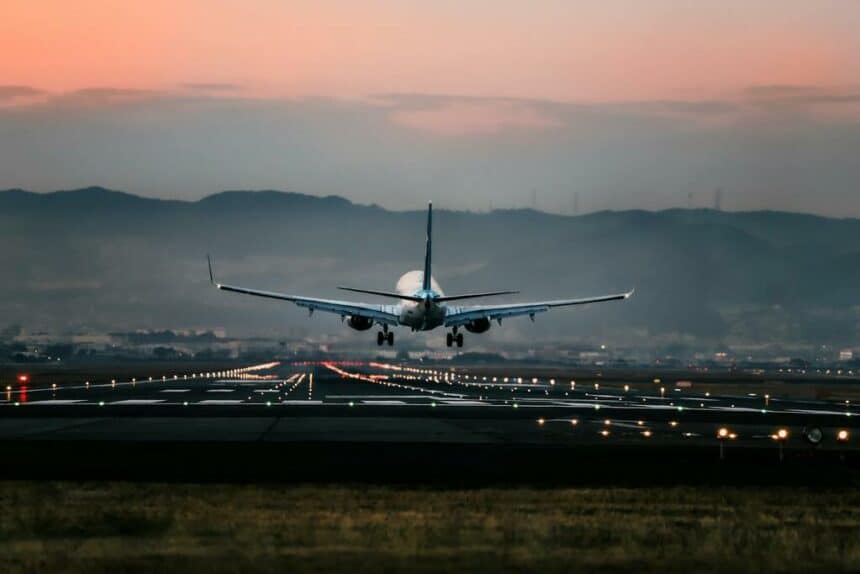 A jet airliner lands in the evening.