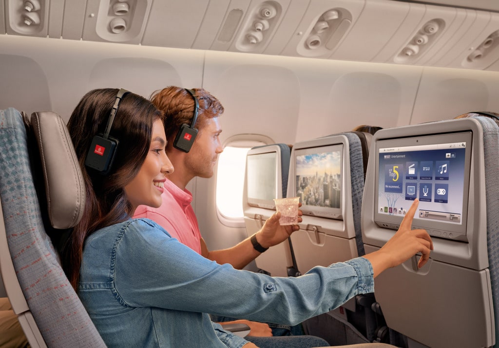 Emirates passengers use entertainment touchscreen on seat back.