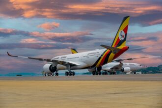 Uganda Airlines aircraft parked at sunset.